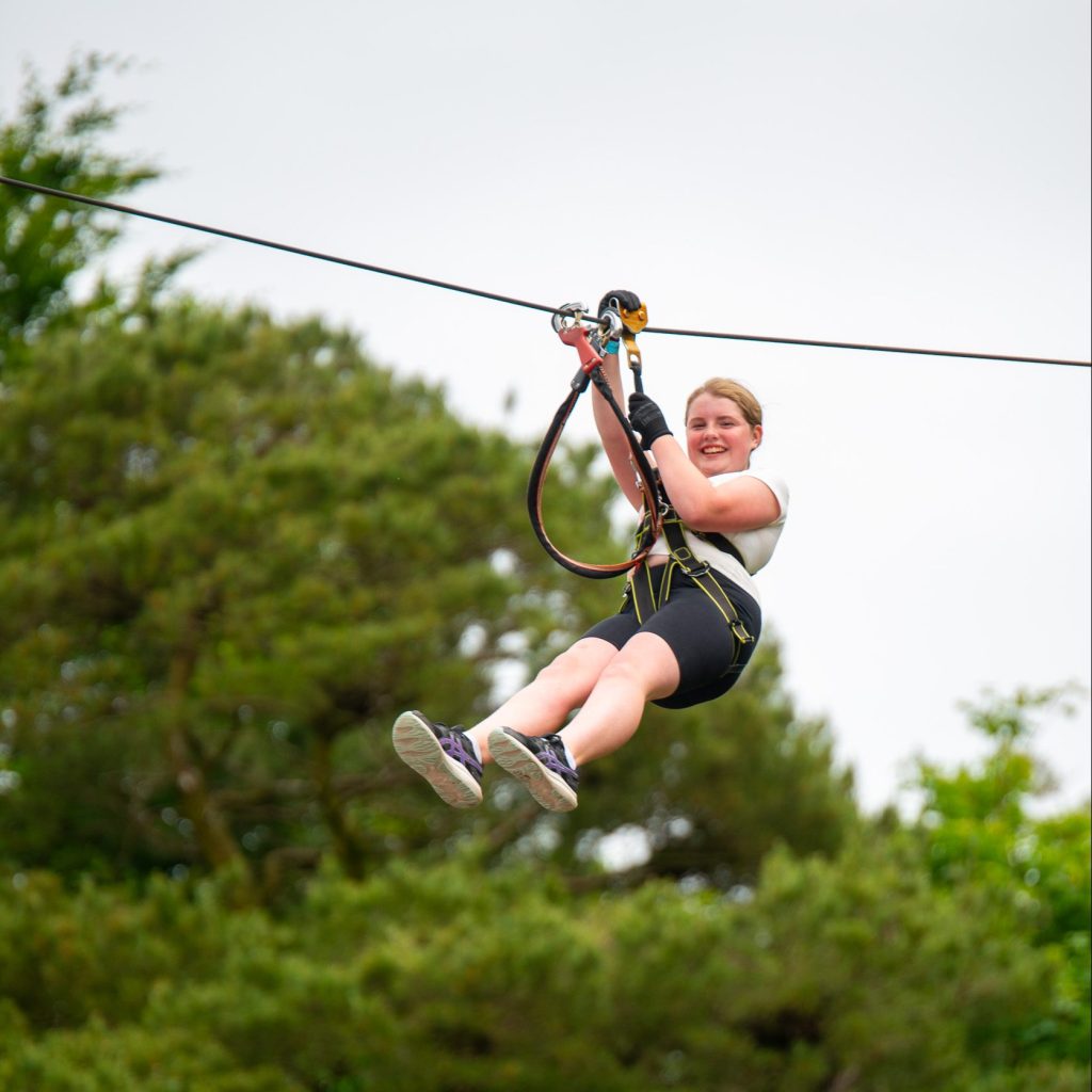 Enjoy a thrilling day at Zipit, soaring through the lush forest canopy. Experience the excitement of ziplining while smiling in your harness and casual clothing. Plan this unforgettable Family Day Out during Summer 2024 for adventure and laughter together!