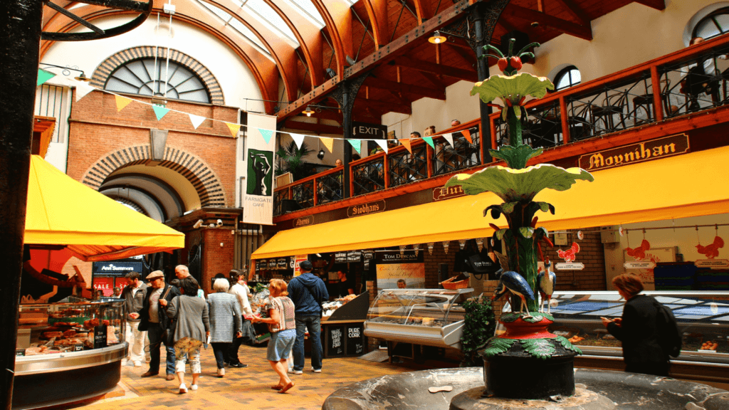 In the charming indoor market, yellow canopies line stalls while a decorative fountain anchors the scene. Shoppers meander beneath arched windows and wooden beams, capturing the essence of Farran Park's vibrant local area.