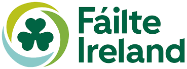 Fáilte Ireland logo featuring a green shamrock inside a circular design with the words “Fáilte Ireland” in bold green text.